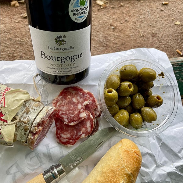 Salami, Oliven, Baguette, eine Flasche Rotwein aus dem Burgund und ein Opinel-Taschenmesser.